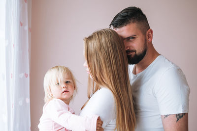 Happy family father young man and mother with baby girl little daughter having fun at home