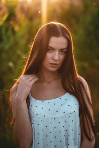 Portrait of young woman standing against plants