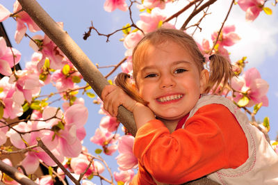 Portrait of happy girl sitting on magnolia tree