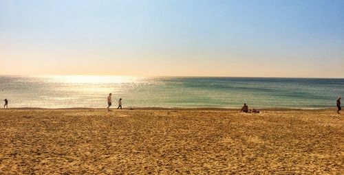 People on beach against sky during sunset