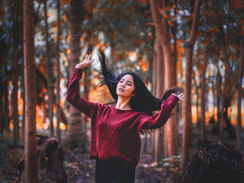 Young woman standing by leaves in forest