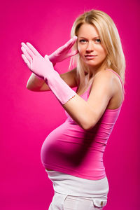 Pregnant woman standing against pink background