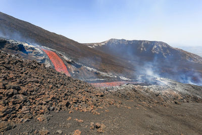 Glowing lava flow flowing on etna volcano in sicily , with smoke and lava flow channel 7 june 2022