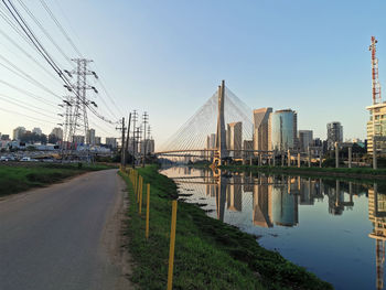 View of bridge over river by buildings against sky