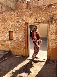 Full length of woman wearing dress standing at doorway of historic building