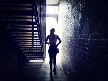 Rear view of woman walking in corridor towards door
