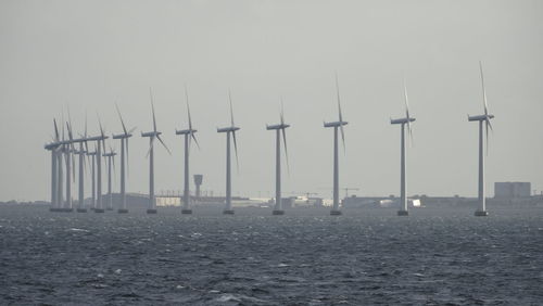 Wind turbines in sea against clear sky