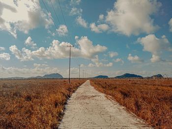 Road amidst field against sky