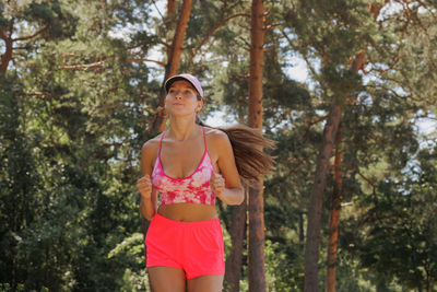 Young woman standing against trees