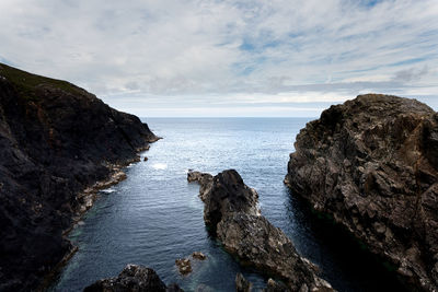 Rock formation on sea shore against sky