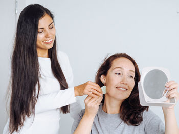 Middle age woman and cosmetologist making massage anti age procedures with guasha stone