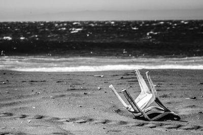 Deck chairs on beach against sky