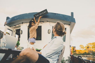 Rear view of man holding woman standing against sky