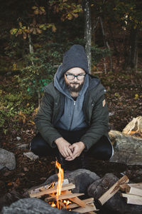 Man crouching at campfire in forest