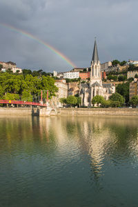View of rainbow over river with buildings in background in  lyon an european city