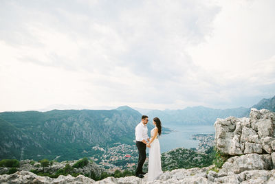 Rear view of man standing on mountain against sky