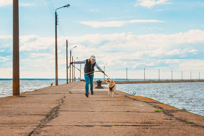 Man with dog on beach against sky