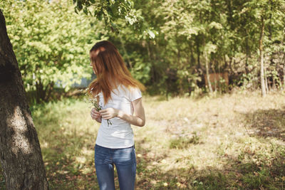 Full length of woman standing on tree trunk