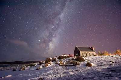 Houses on snowcapped mountain against sky at night