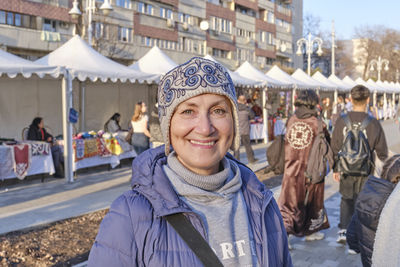 Portrait of senior caucasian woman, wearing felt cap with kazakh embroidered pattern, at crafts fair