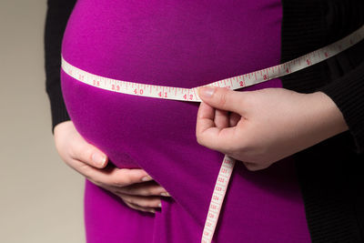 Midsection of pregnant woman with tape measure