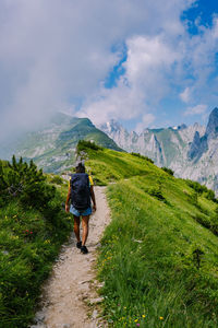 Rear view of woman walking on trail against mountain range