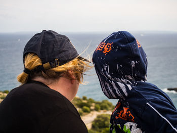 Rear view of people on sea shore against sky