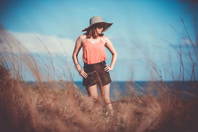 Woman wearing hat standing on field against sky