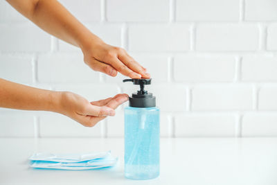 Close-up of hand holding bottle against wall