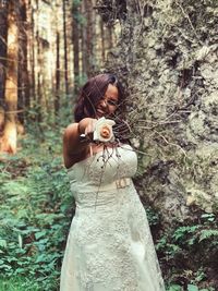 Woman standing by tree in forest