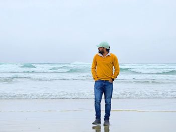 Lone man standing on beach against sky in tranquility