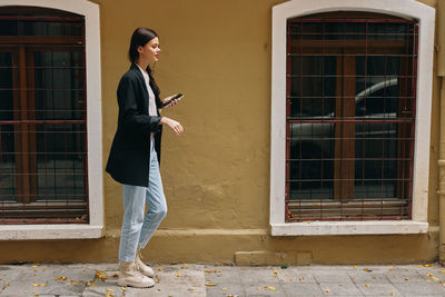 Side view of young man standing against wall