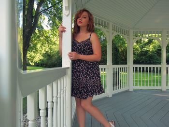 Portrait of young woman leaning on railing at gazebo in park