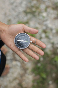 Close-up of woman holding navigational compass on field