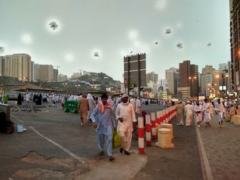 People walking on street in city against sky