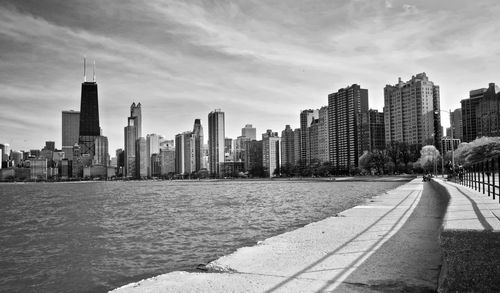 Sea by modern buildings against sky in city