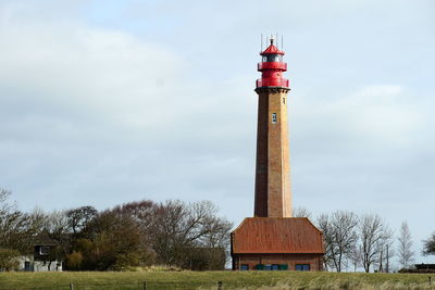 Lighthouse by building against sky