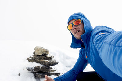 Portrait of man with stacked stones on snow covered field