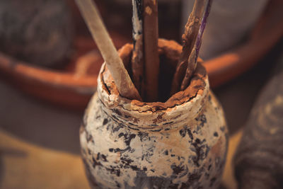 Glass, clay smeared smeared with brushes. a glass stained with smeared clay with tassels on table. 