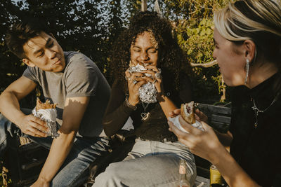 Young woman eating food with friends in park