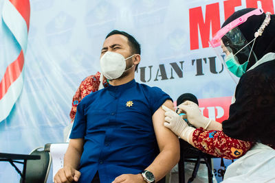 Man wearing mask getting vaccinated