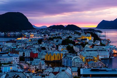 High angle view of townscape by sea against sunset sky