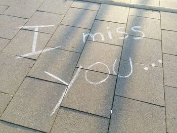 High angle view of i miss you text on footpath