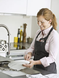 Smiling woman washing dishes