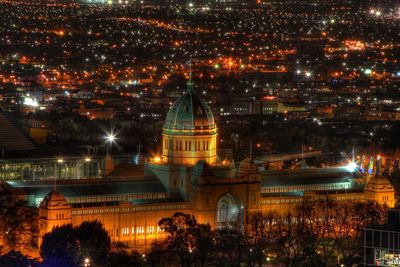 Illuminated royal exhibition building and cityscape at night