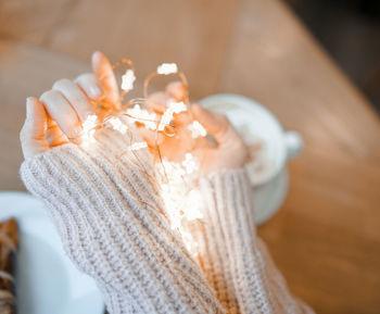 Close-up of woman holding illuminated string light