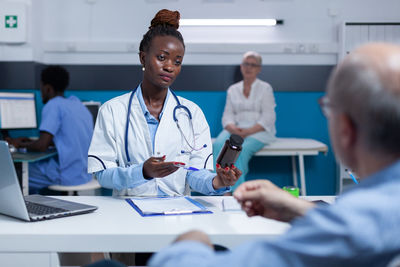 Female doctor giving medicine to patient in hospital