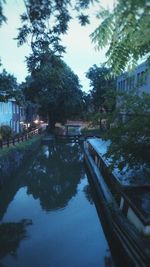Canal amidst trees against sky