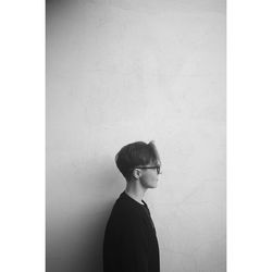 Profile view of young man standing by wall