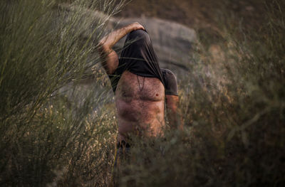 Man covering head with shirt in wood